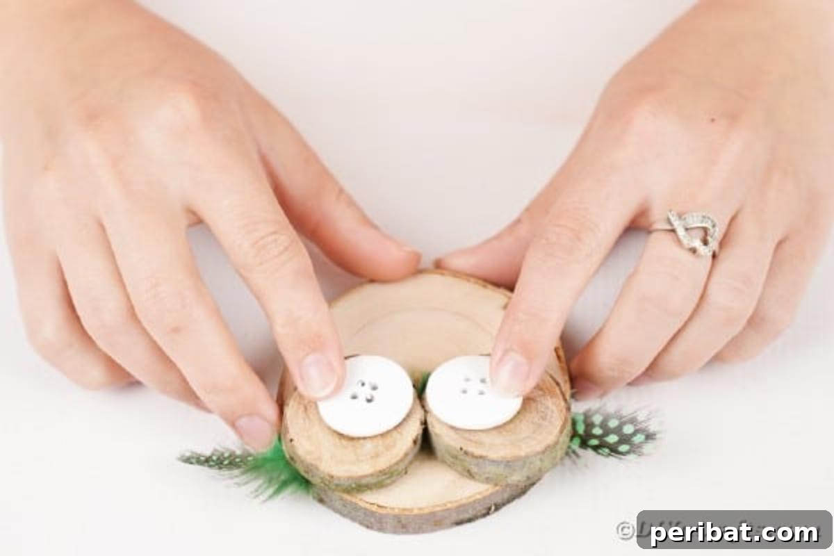 Whimsical Wooden Owls from Recycled Scraps Video Guide 10 Crafting process captured: large buttons are being carefully glued onto the center of the small wooden slices, forming the distinct eyes of the decorative owl.