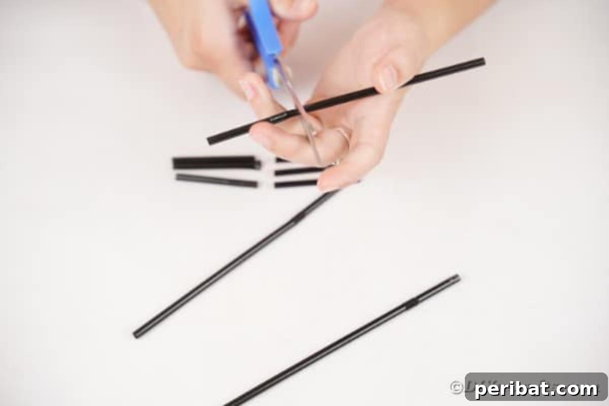 A hand cutting a black straw into smaller segments with scissors, preparing them for the hedgehog craft.