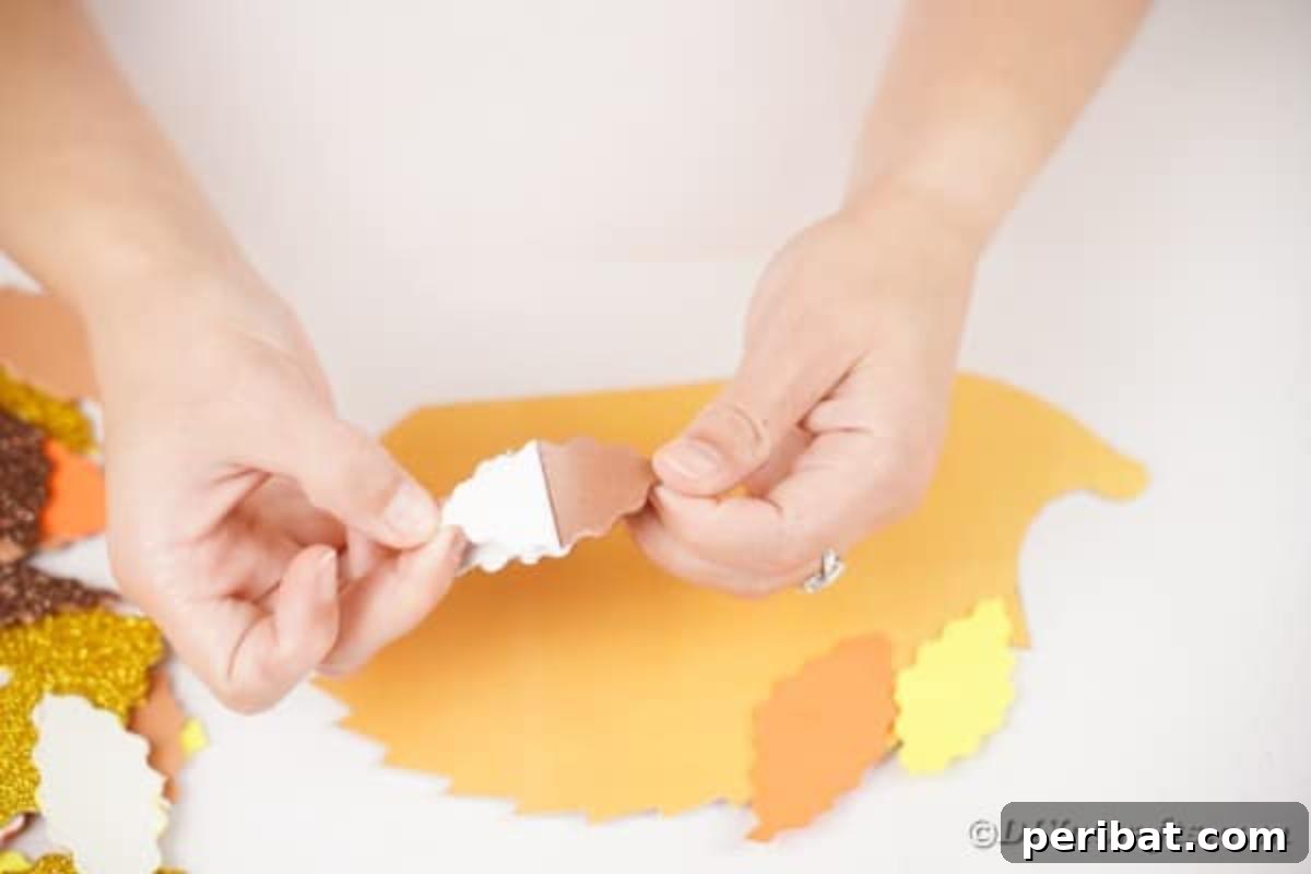 A hand attaching the first few foam paper leaves to the top of the hedgehog template.
