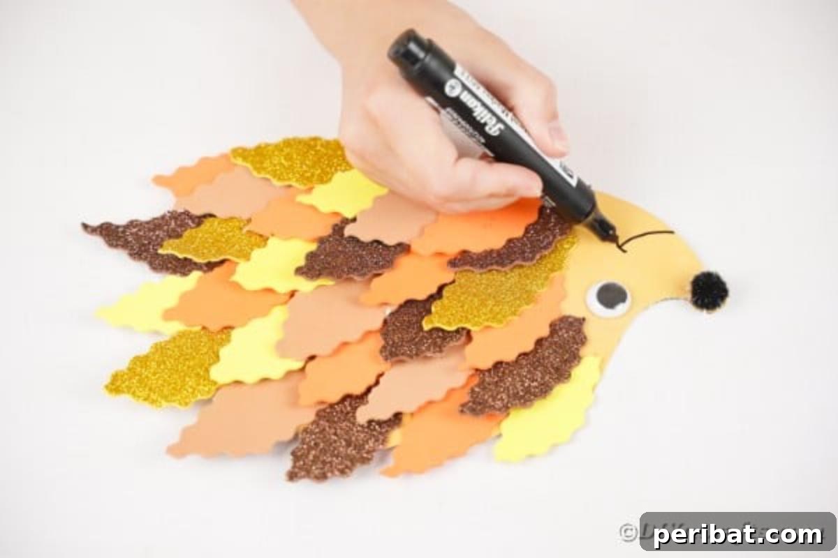 A black marker drawing a smile onto the face of the paper leaf hedgehog.