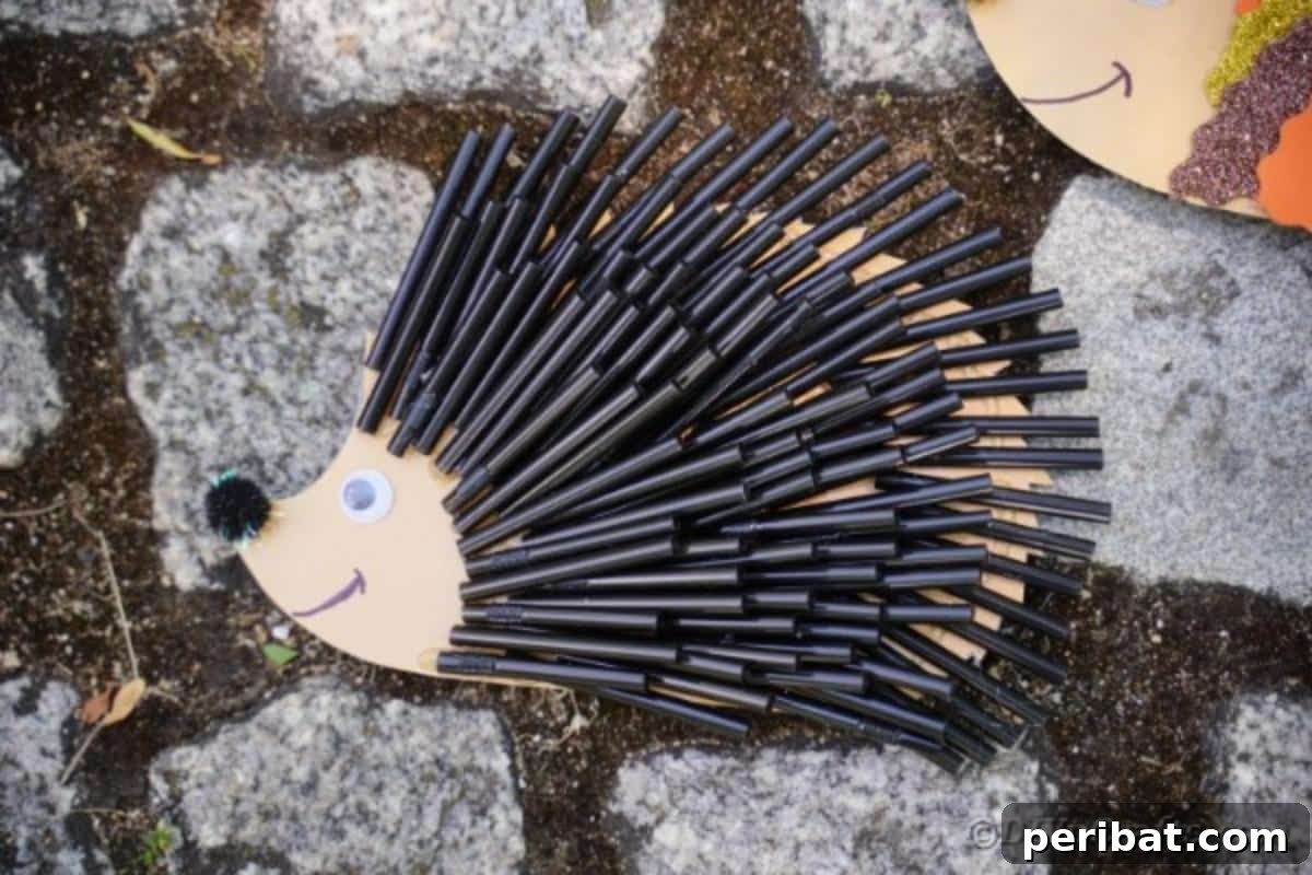 A finished hedgehog craft made from black straw pieces, carefully placed on a rustic cobblestone surface, capturing its textured quills.