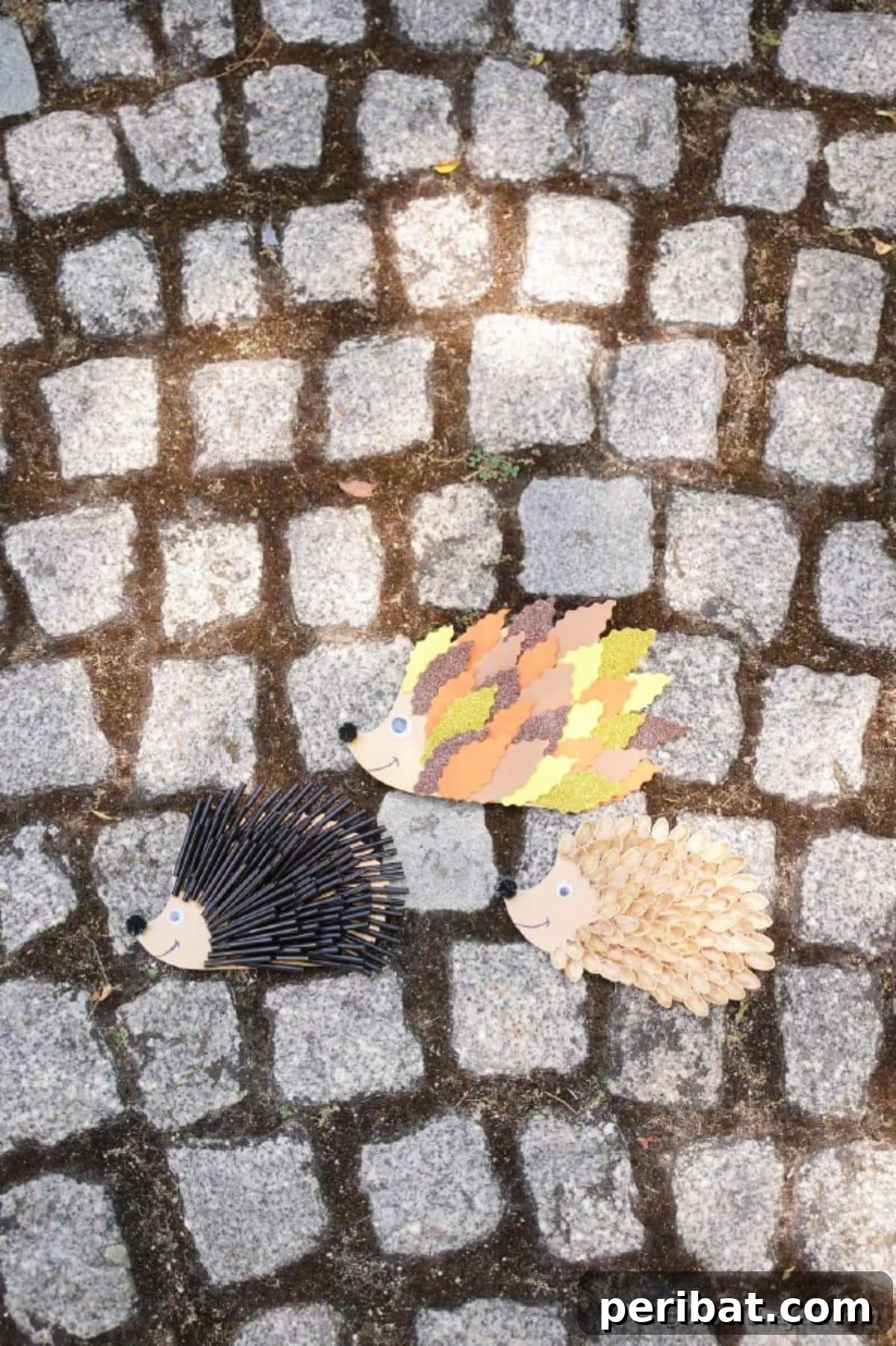 A collection of three hedgehog crafts (pistachio shell, paper leaf, black straw) arranged on a rustic cobblestone surface, highlighting their variety.