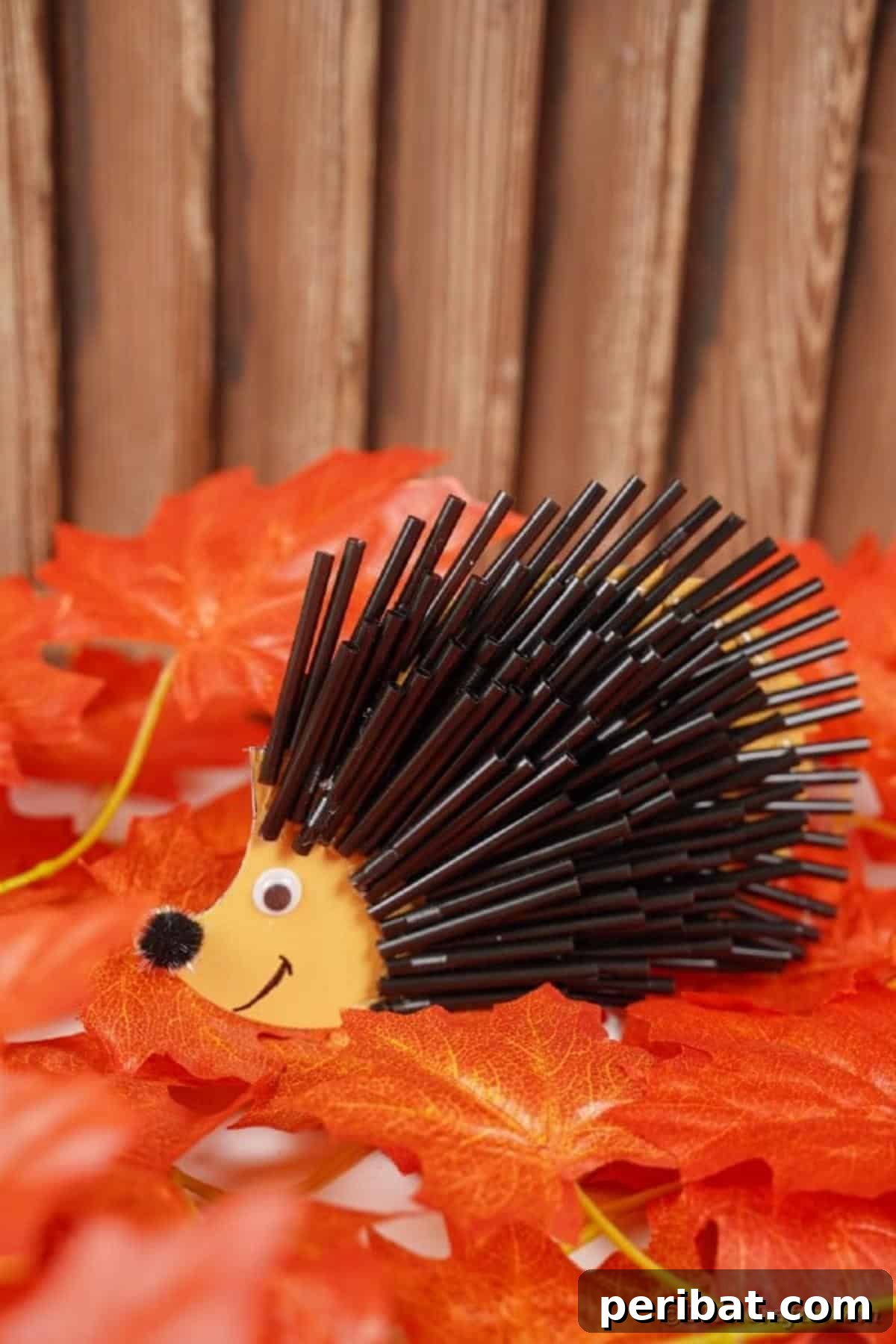 A black straw hedgehog craft nestled among fall leaves, emphasizing its natural look and seasonal appeal.