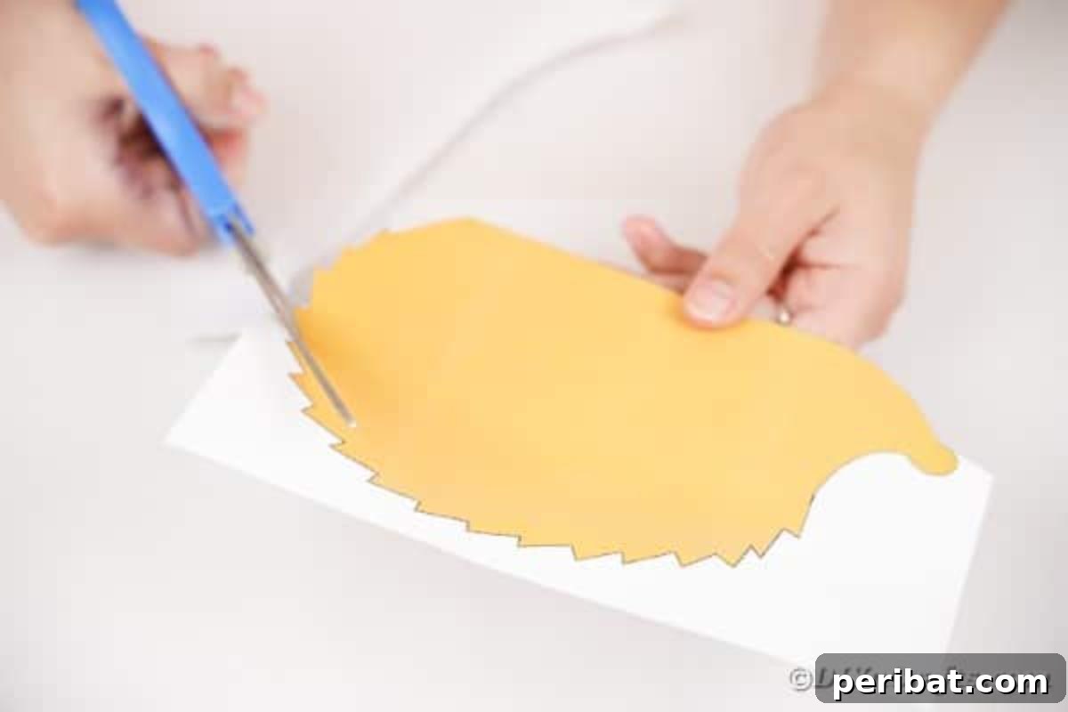 A hand using scissors to cut out the hedgehog shape from the printed template.