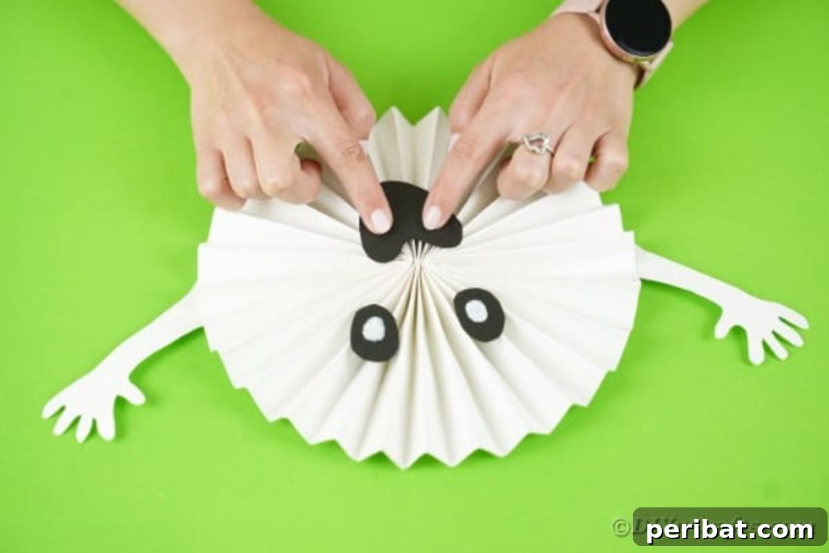 Fun and Easy Halloween Paper Fan Decor 20 Gluing face onto ghost fan