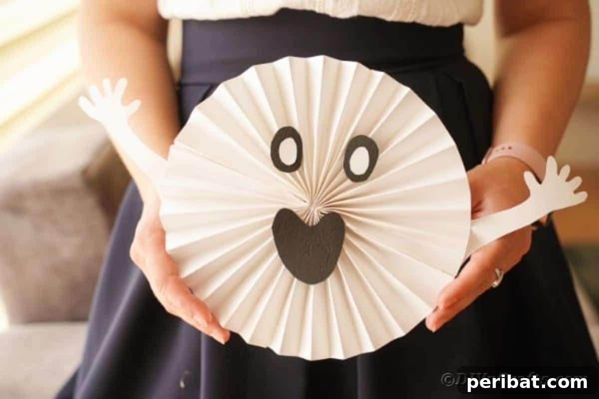 Fun and Easy Halloween Paper Fan Decor 21 Woman holding paper ghost decoration