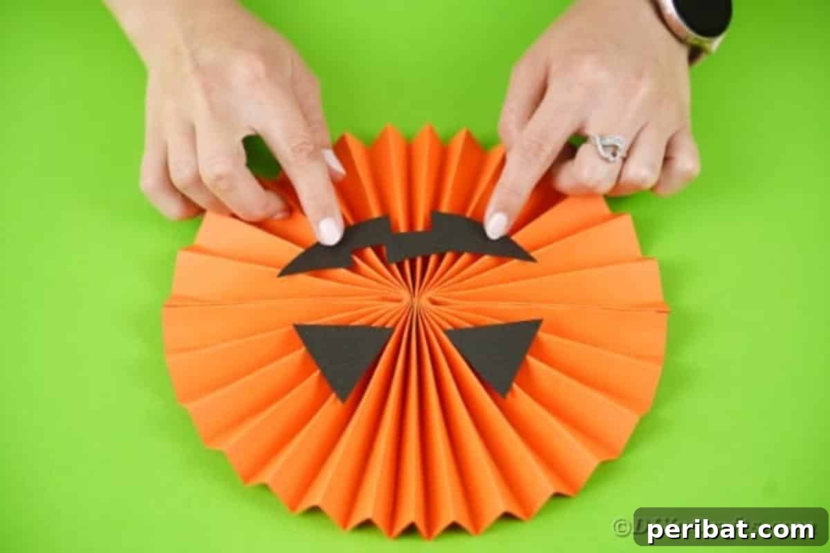 Fun and Easy Halloween Paper Fan Decor 23 Gluing mouth onto pumpkin paper fan