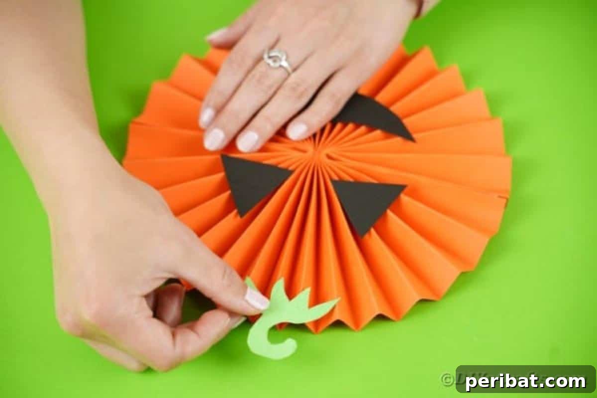 Fun and Easy Halloween Paper Fan Decor 24 Gluing stem onto paper pumpkin