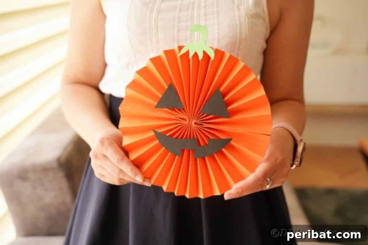 Fun and Easy Halloween Paper Fan Decor 26 Woman holding paper fan pumpkin