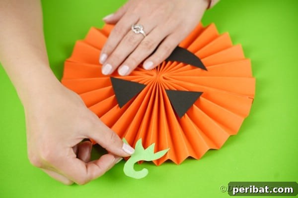 Fun and Easy Halloween Paper Fan Decor 38 Gluing stem onto paper pumpkin