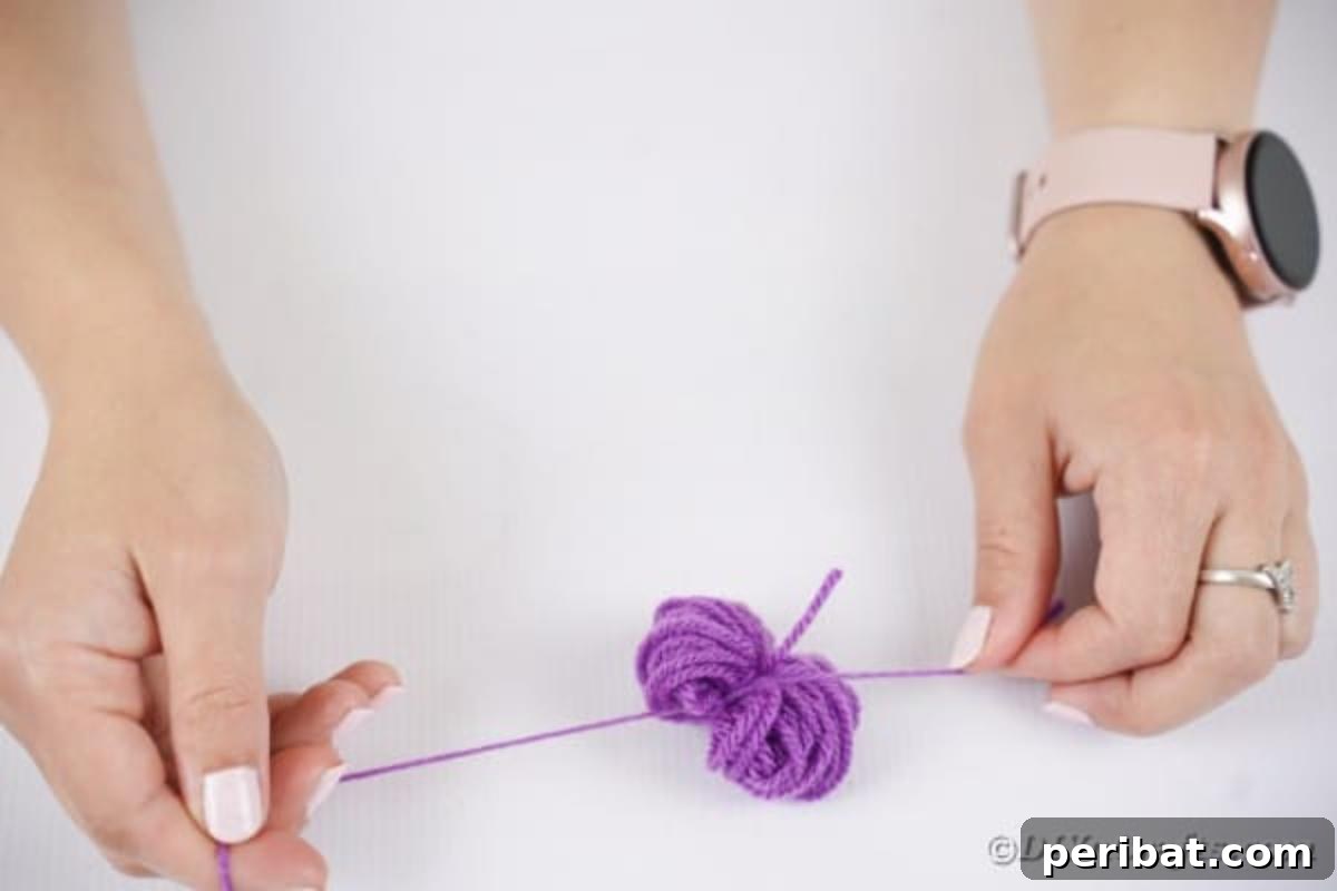 Spooktacular Clothespin Monster Craft 11 A hand tying a piece of yarn around the center of a wound yarn ball