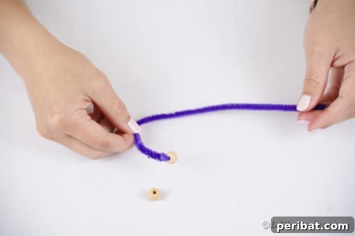 Spooktacular Clothespin Monster Craft 13 A hand adding a pony bead to the end of a purple pipe cleaner