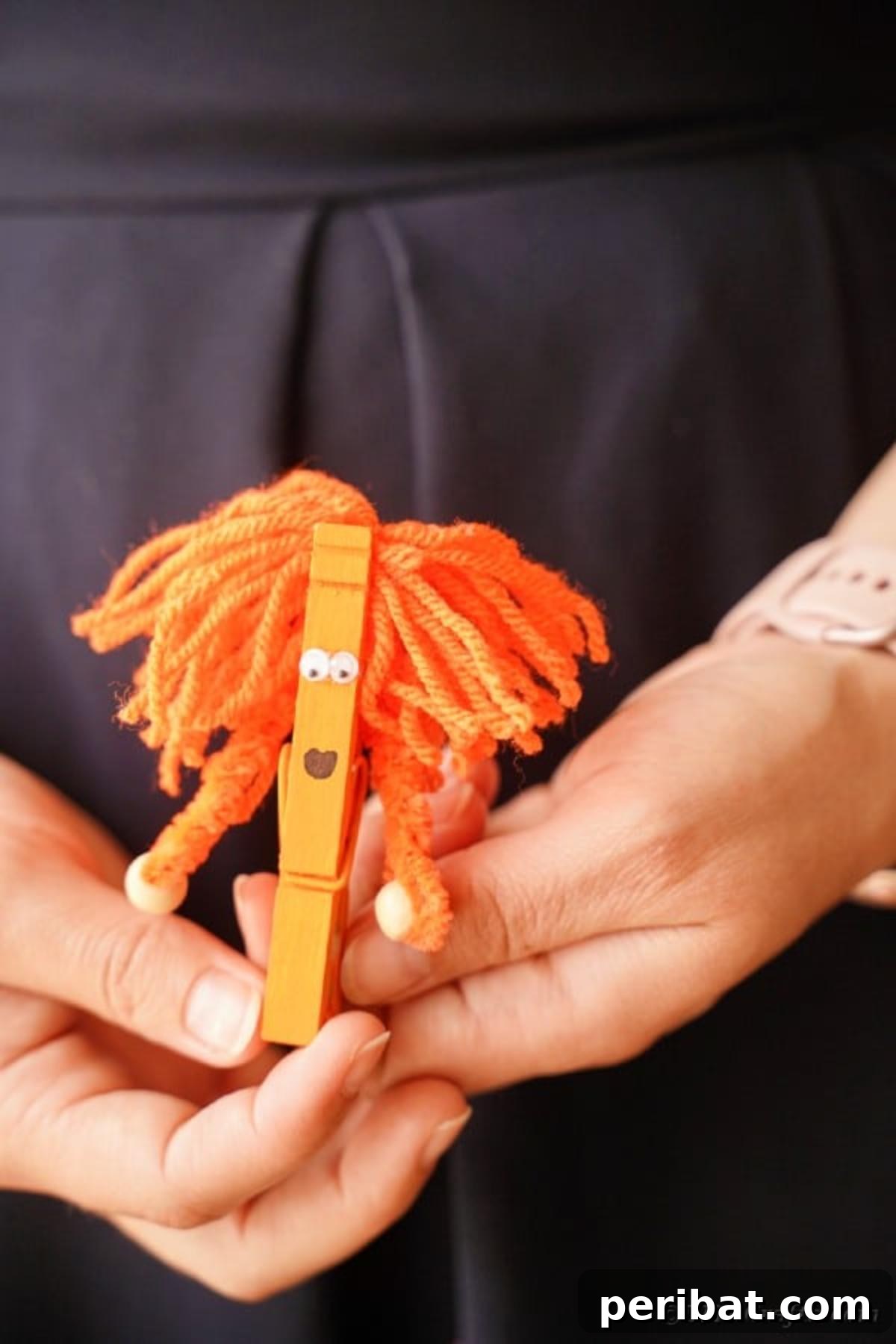 Spooktacular Clothespin Monster Craft 21 A woman's hand holding a vibrant orange clothespin monster