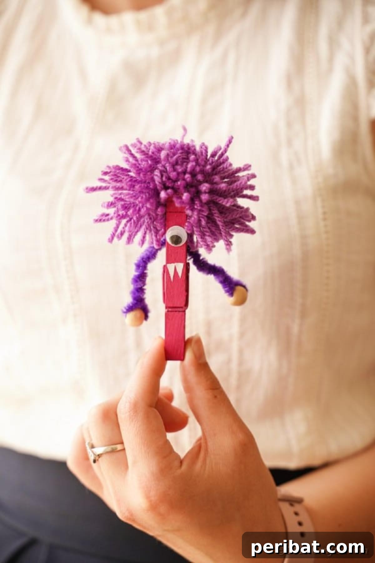 Spooktacular Clothespin Monster Craft 22 A woman's hand holding a charming purple clothespin monster