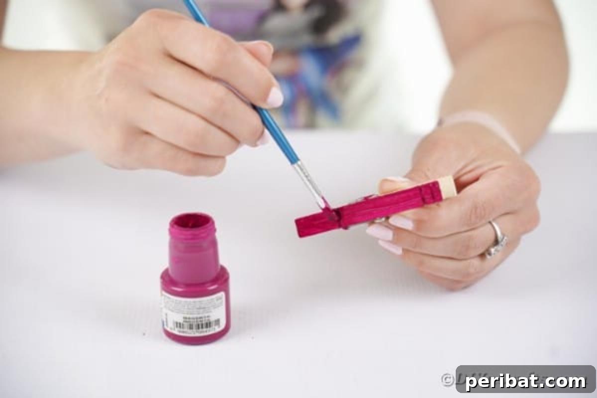 Spooktacular Clothespin Monster Craft 8 A person painting a wooden clothespin purple