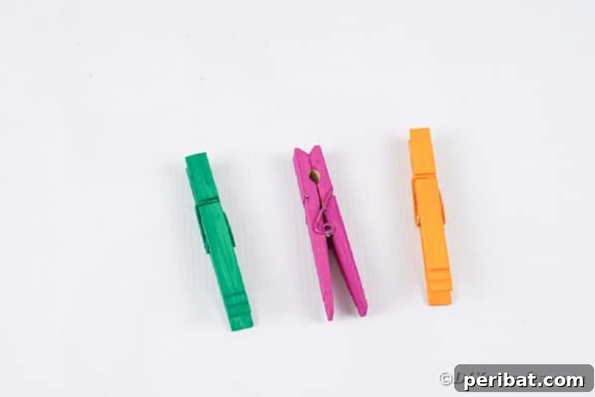 Spooktacular Clothespin Monster Craft 9 Several painted clothespins in purple, green, and orange drying on a white table