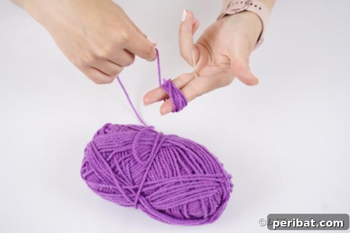 Spooktacular Clothespin Monster Craft 10 Hands winding orange yarn around fingers to create a pom-pom
