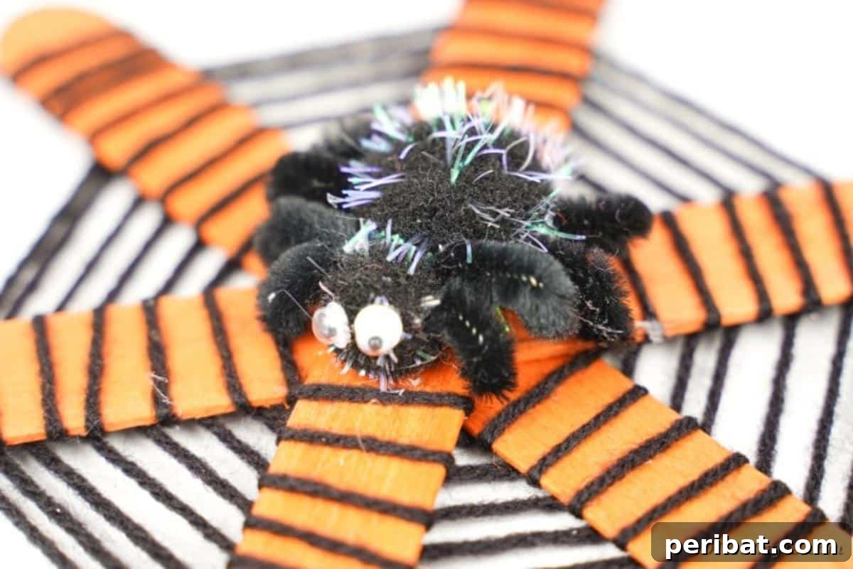 Spooky Stick Spiderwebs 3 A beautifully crafted spider web made from craft sticks and yarn, resting on a clean white surface.