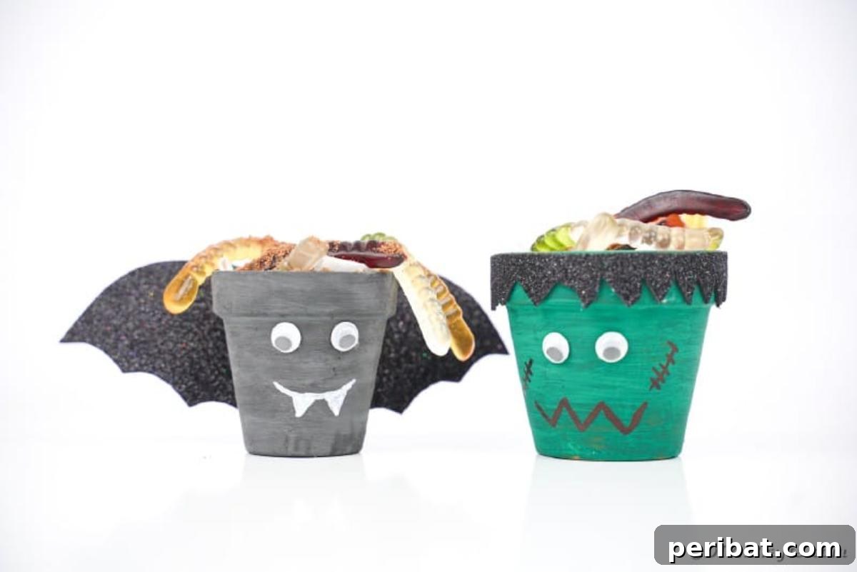 Charming Upcycled Planter Halloween Pals 3 Upcycled flower pot Halloween characters, a bat and Frankenstein, displayed on a white table next to candy.
