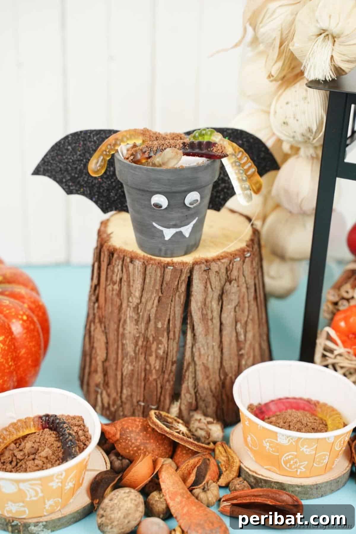 Charming Upcycled Planter Halloween Pals 21 A finished bat flower pot Halloween character with googly eyes and fangs, placed on a tree stump outdoors.