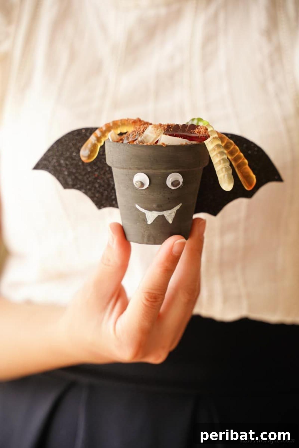 Charming Upcycled Planter Halloween Pals 23 A woman holding a finished bat flower pot character, showcasing its cute design.