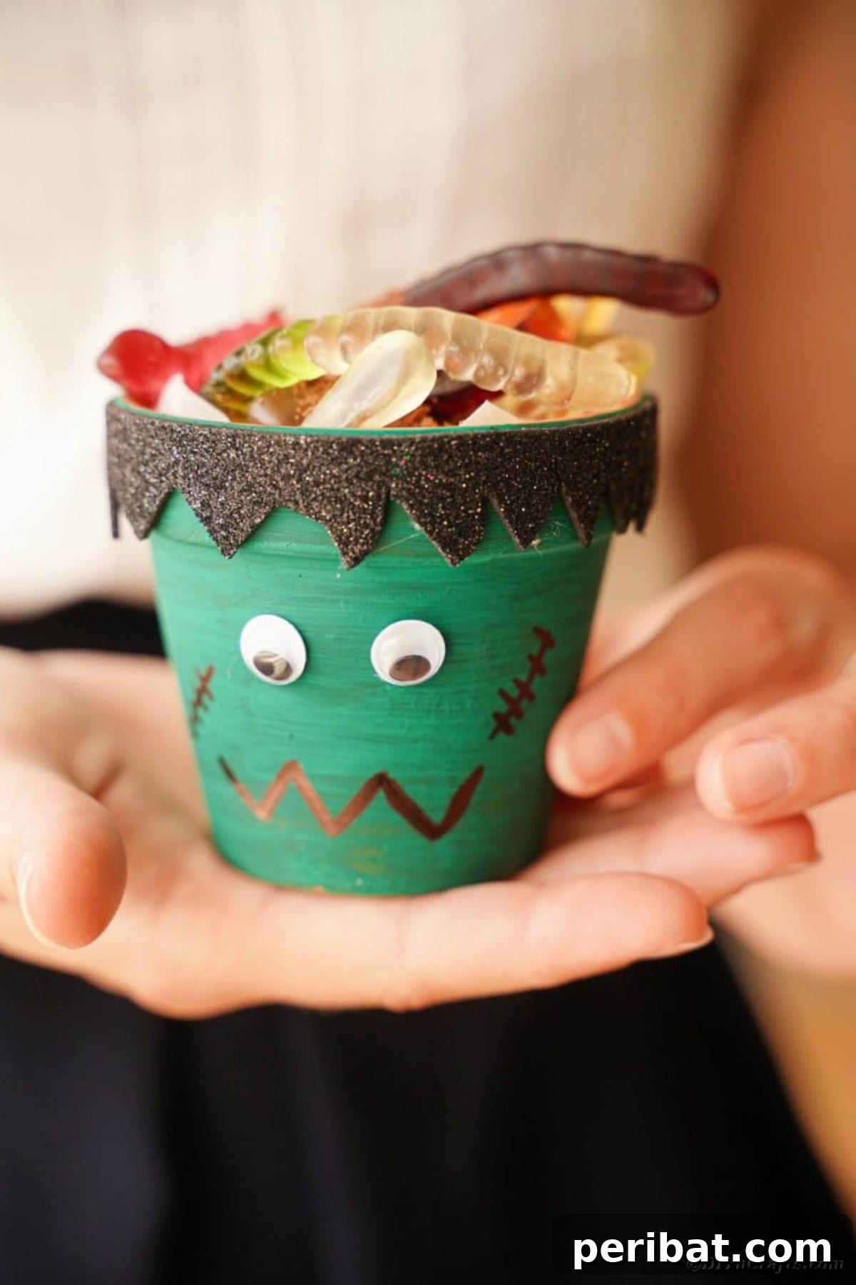 Charming Upcycled Planter Halloween Pals 24 A woman holding a finished Frankenstein flower pot character, demonstrating its festive appeal.