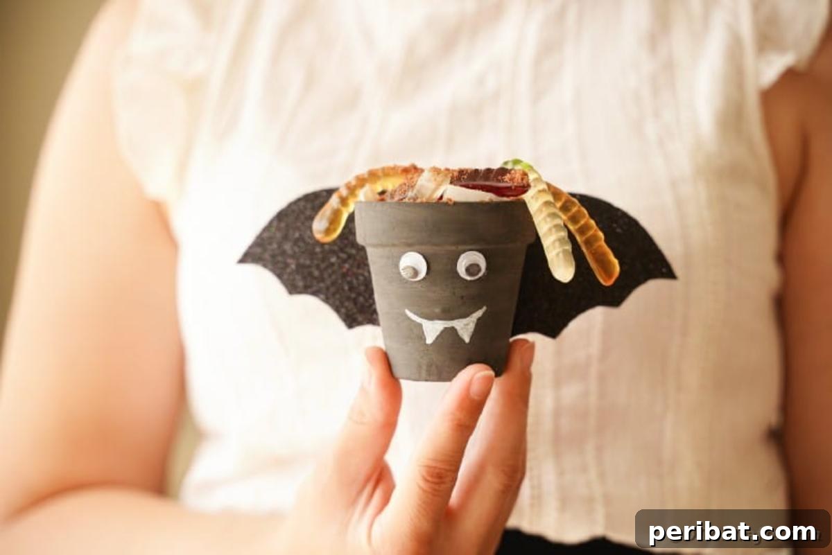Charming Upcycled Planter Halloween Pals 5 A woman holding a finished bat-themed upcycled flower pot Halloween character.