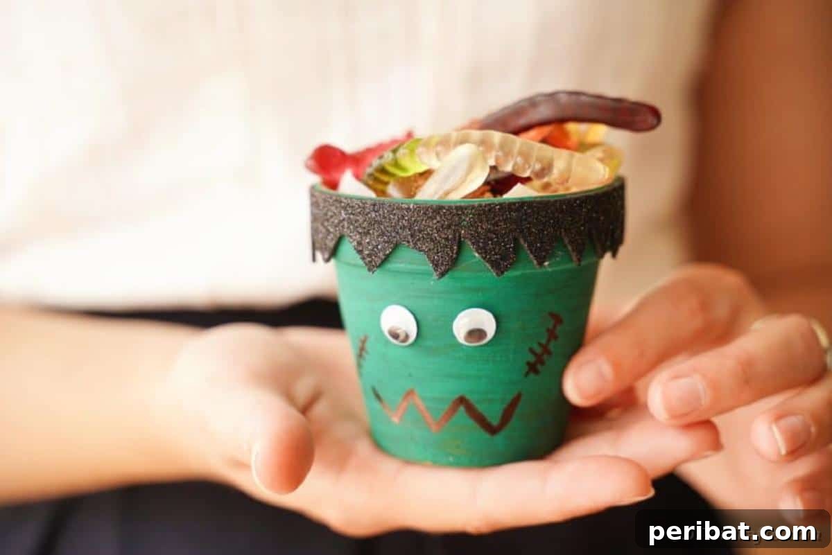Charming Upcycled Planter Halloween Pals 7 A woman holding a finished Frankenstein-themed upcycled flower pot Halloween character.