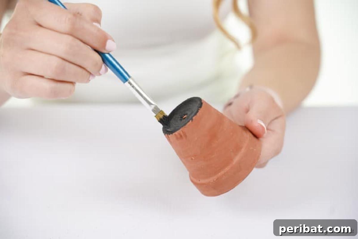 Charming Upcycled Planter Halloween Pals 9 A terracotta flower pot being painted black as the base for a Halloween character.