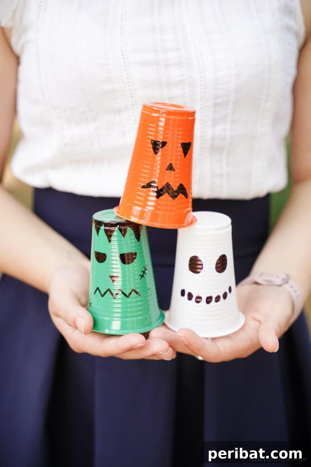 A person holding a variety of finished plastic cup Halloween lanterns, ready for display.