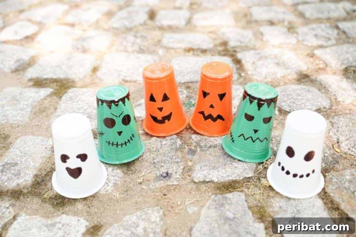 A collection of plastic cup Halloween lanterns designed as classic characters on a cobblestone surface.