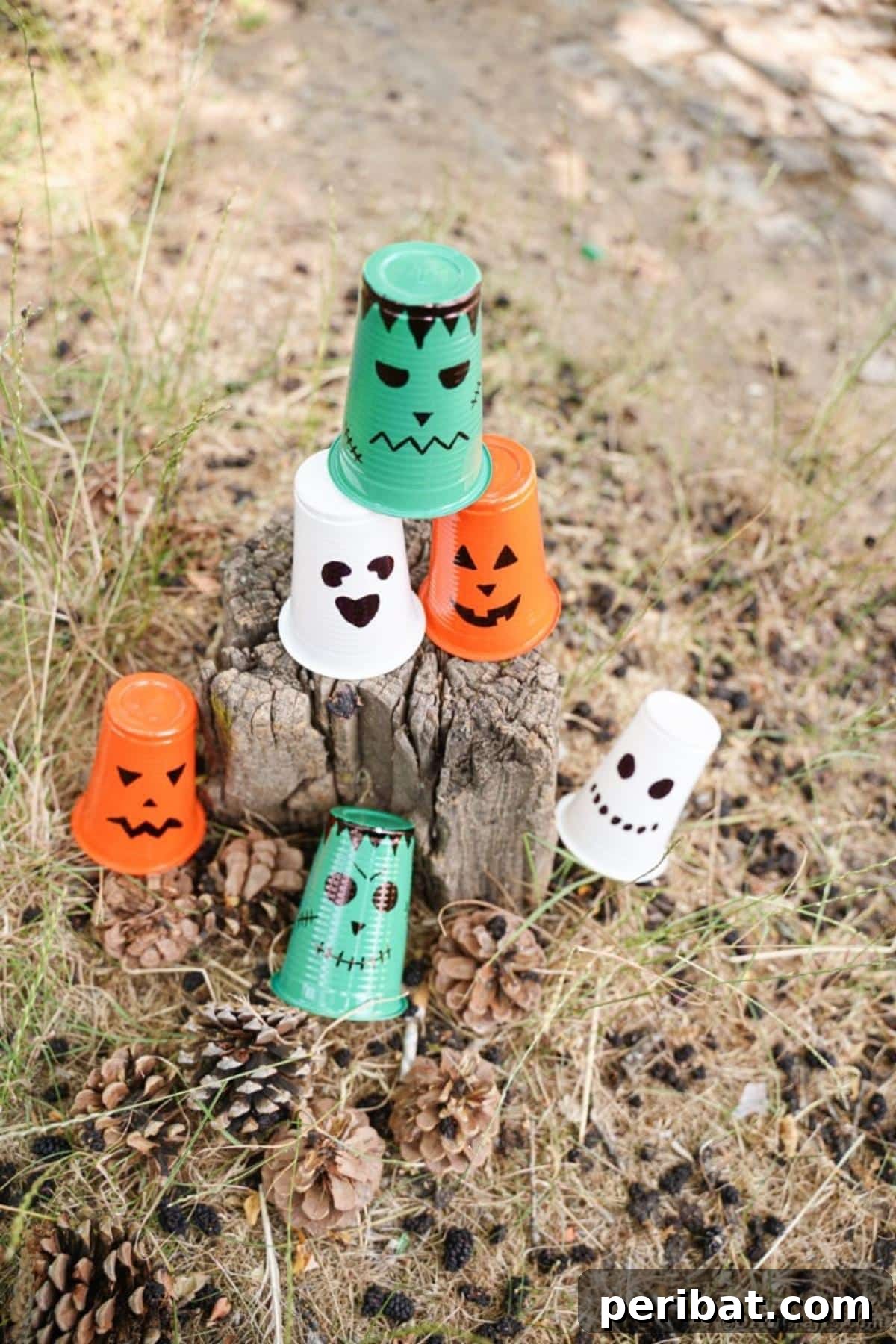Plastic cup Halloween lanterns displayed on a wooden tree stump outdoors, adding rustic charm.