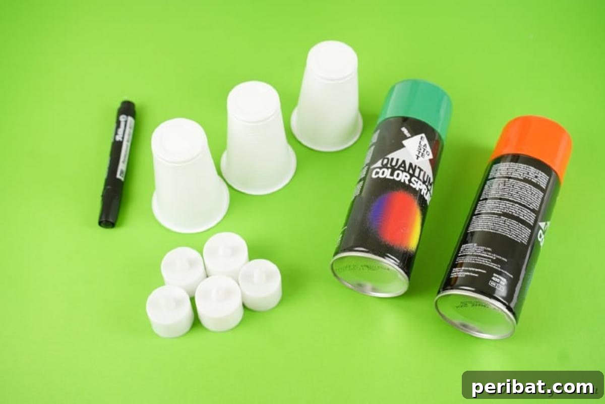 The essential supplies laid out for crafting plastic cup Halloween lanterns.