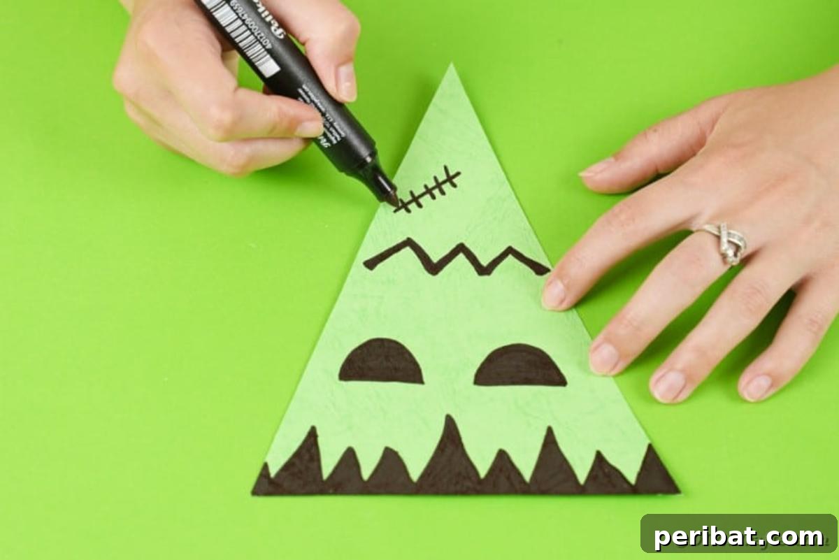 Green paper triangle decorated with a hand-drawn Frankenstein monster face