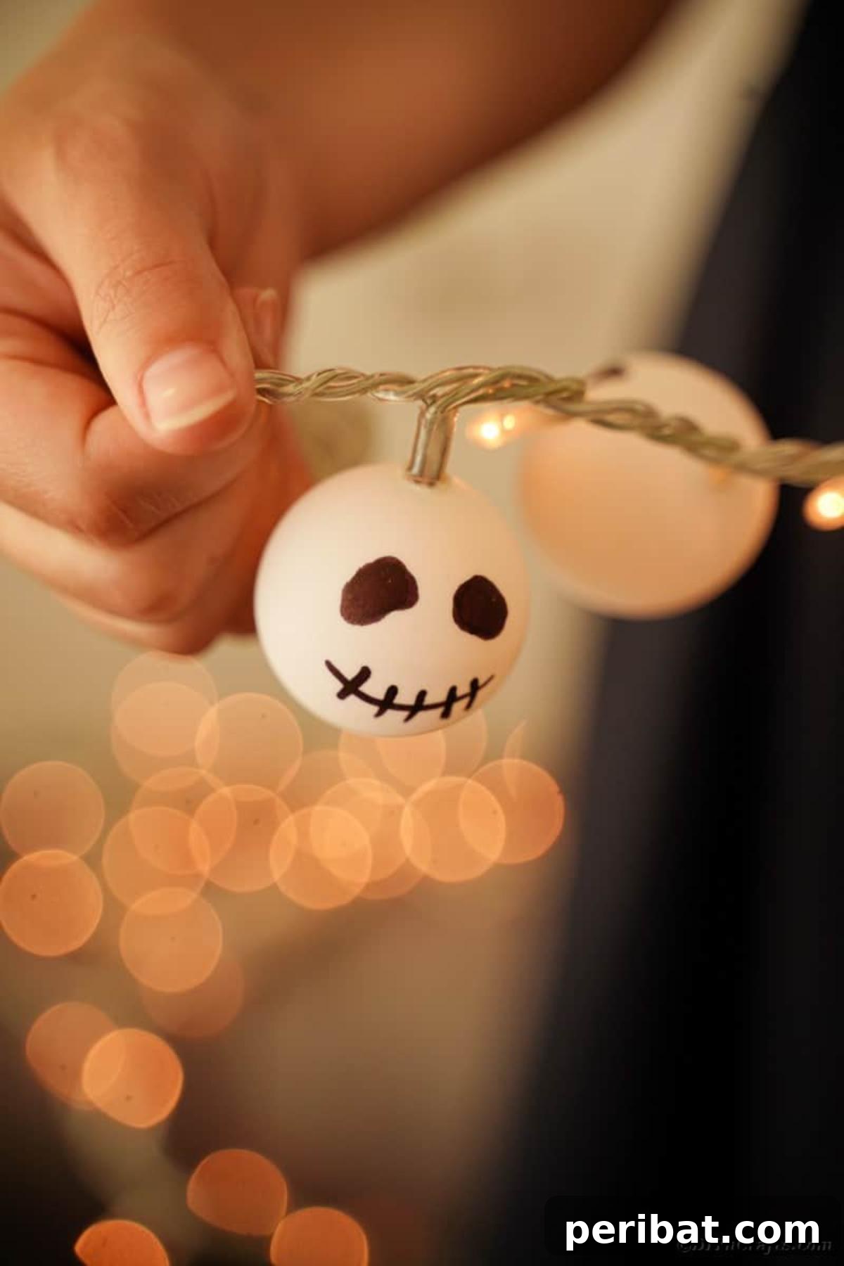 DIY Jack Skellington Halloween Garland with Ping Pong Balls 16 Woman holding Jack Skellington garland