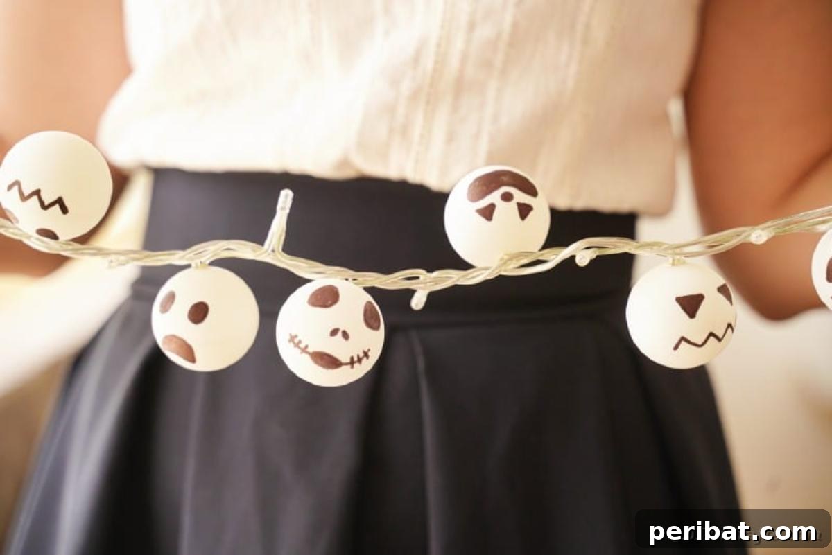 DIY Jack Skellington Halloween Garland with Ping Pong Balls 7 Woman holding Jack Skellington garland