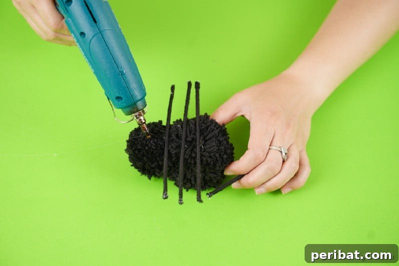 Gluing legs onto pom poms