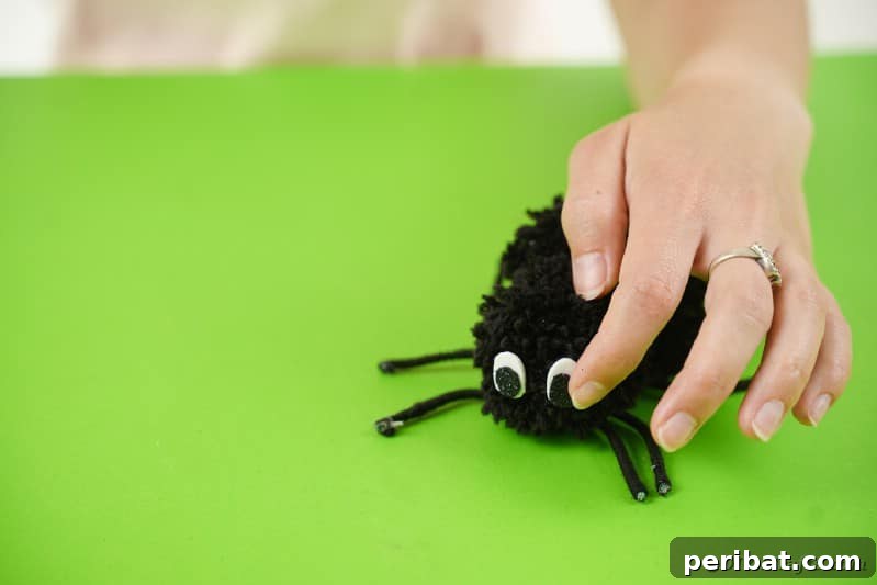 Gluing eyes onto pom pom spider