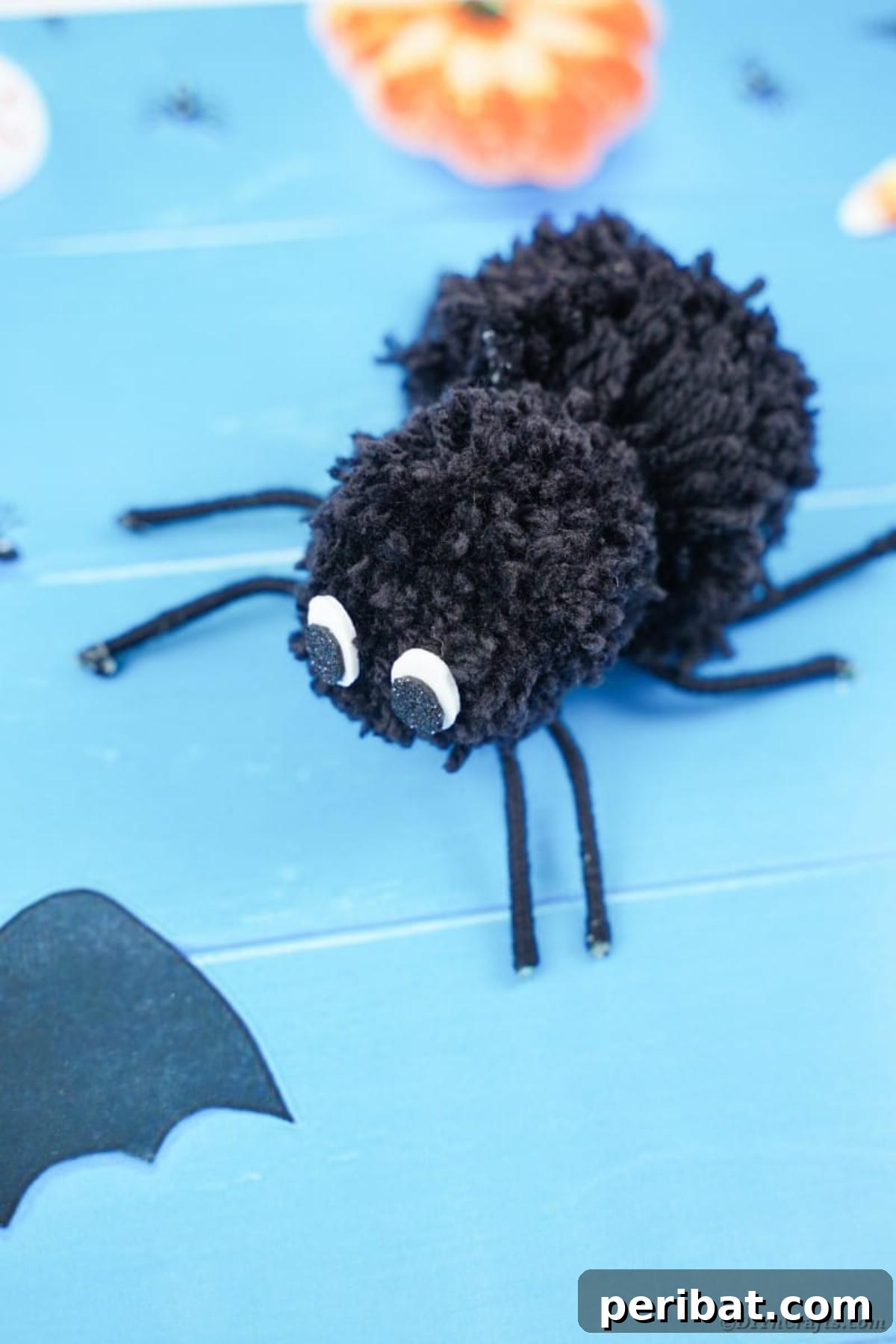 Pom pom spider on blue halloween paper
