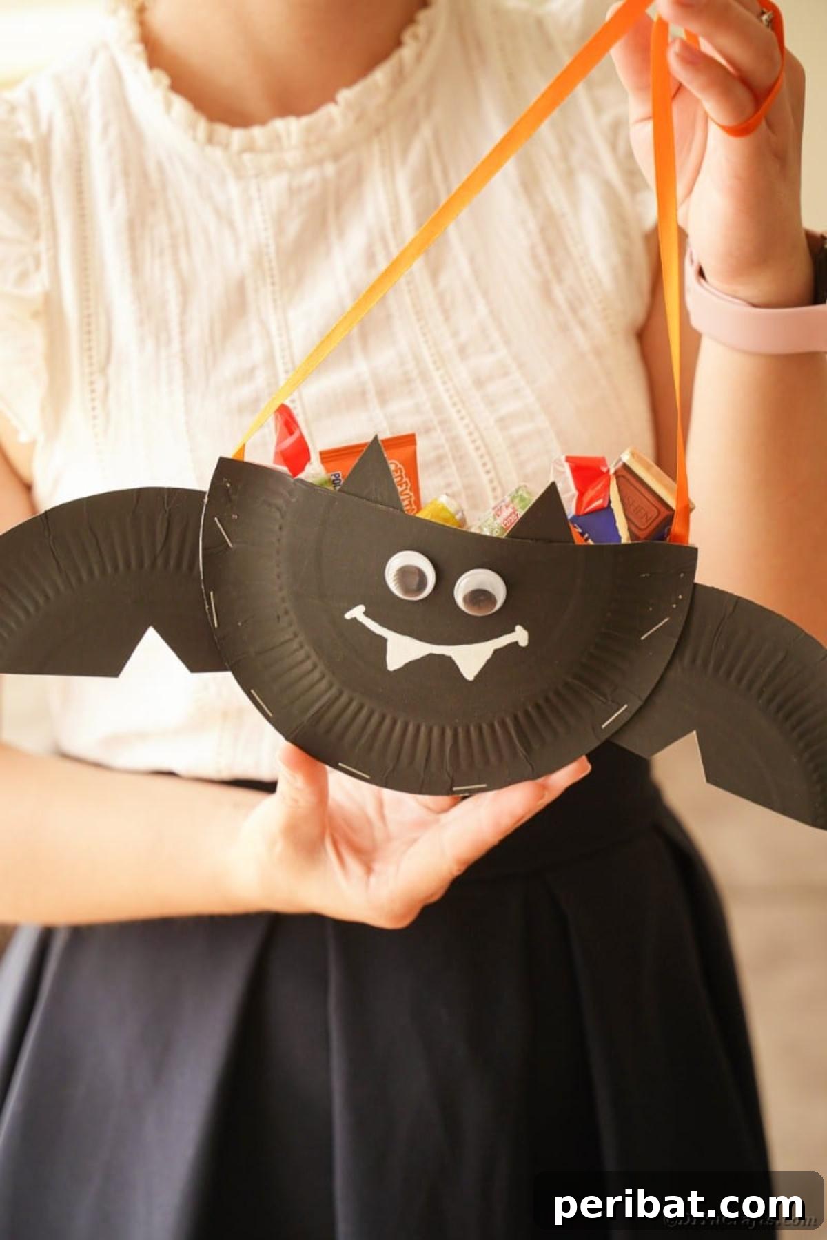 DIY Paper Plate Bat Candy Catchall 21 Woman holding a paper plate bat filled with candy