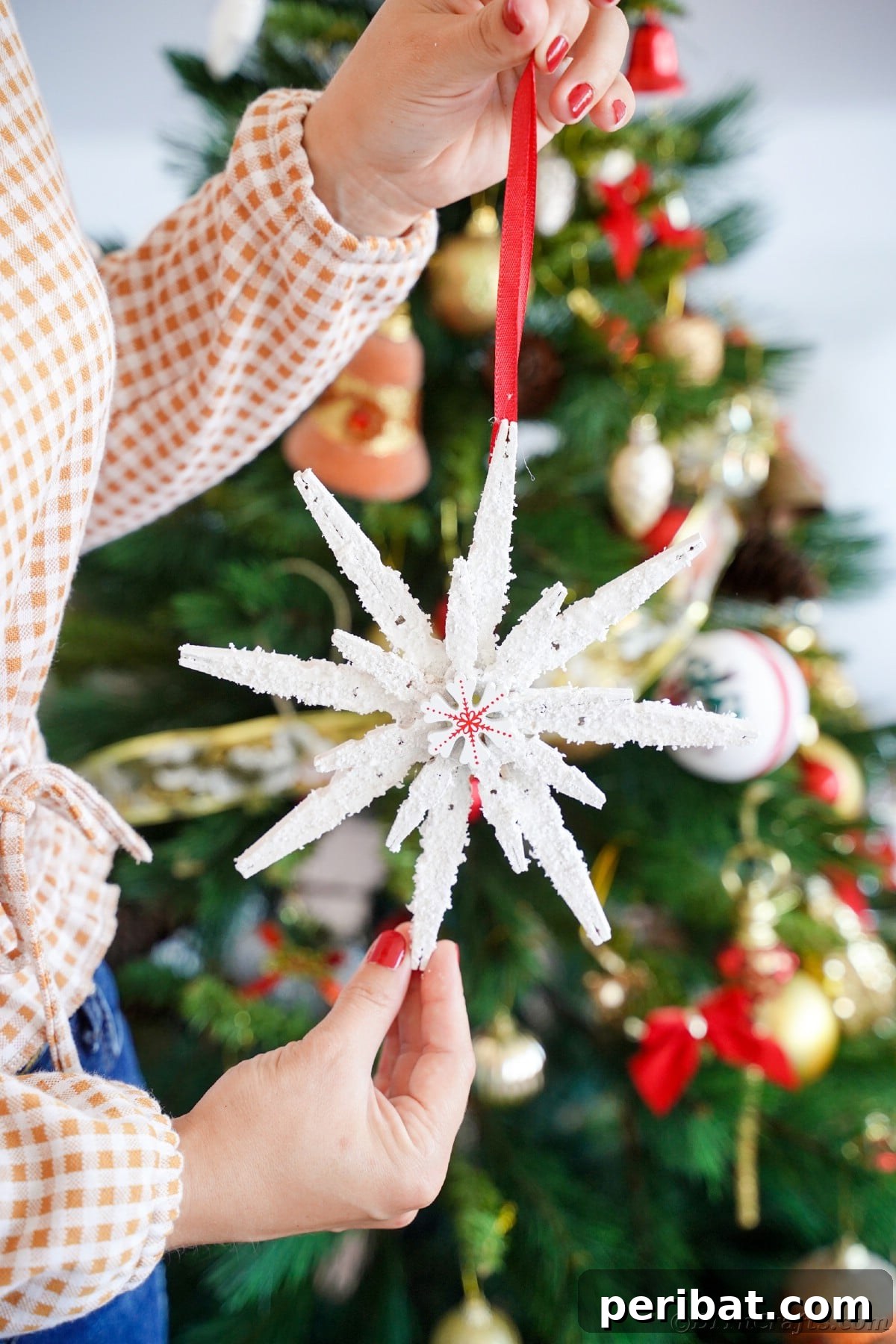woman holding clothespin snowflake in front of tree
