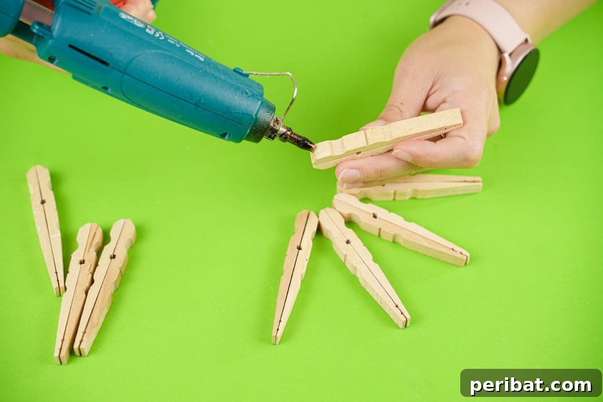 hot glue gun applying glue to wooden clothespins in hand 