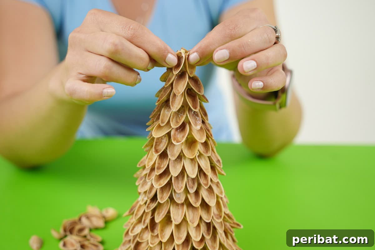 DIY Mini Christmas Trees from Upcycled Pistachio Shells 12 Woman arranging pistachio shells on the DIY Christmas tree