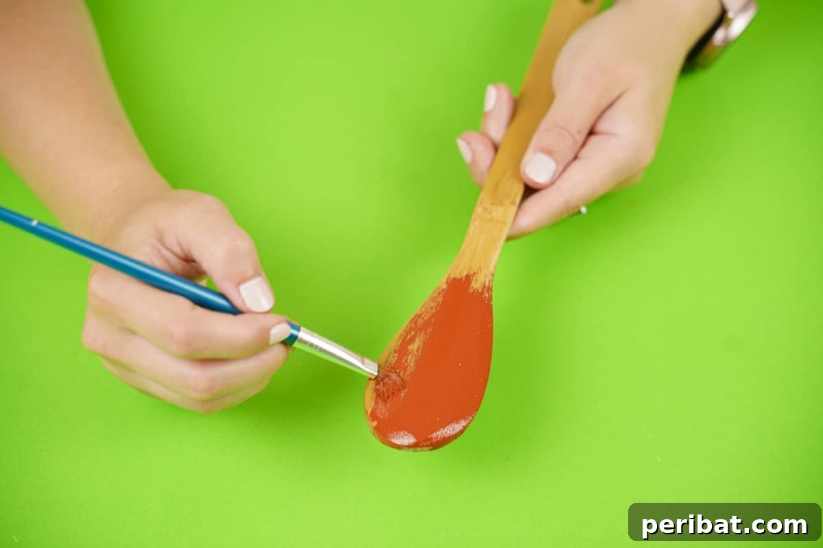 Painting red paint onto a wooden spoon Christmas craft