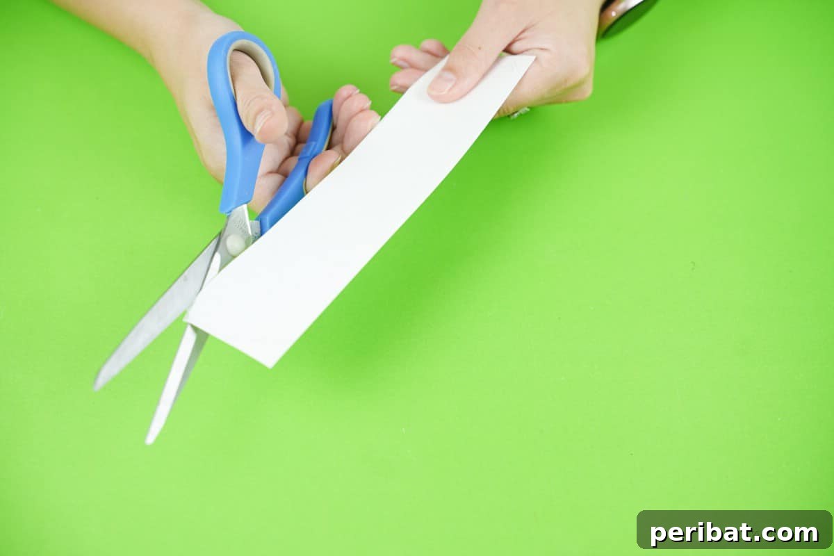 Craft a Delightful Santa Hat Wreath for Christmas 11 Cutting the white paper for the Santa hat brim with scissors.