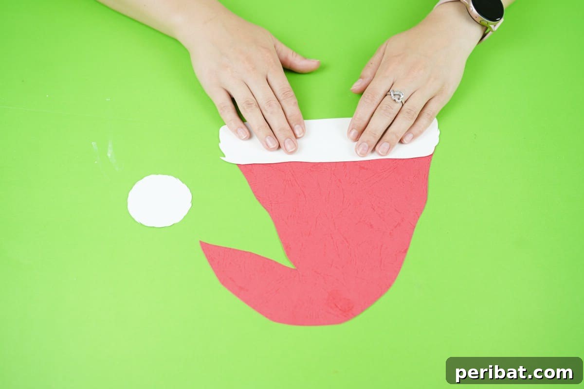 Craft a Delightful Santa Hat Wreath for Christmas 12 Applying paper with glue to craft the Santa hat, adding the brim and pom-pom.