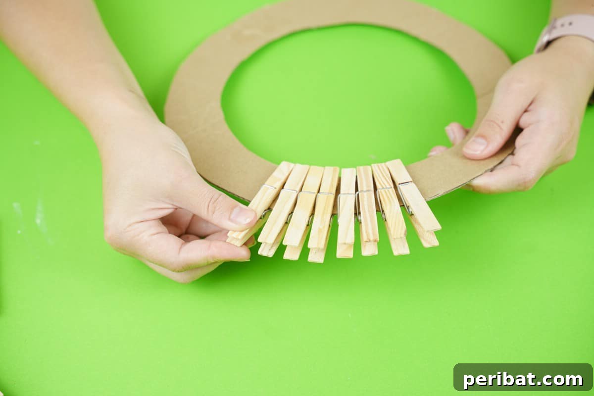 Craft a Delightful Santa Hat Wreath for Christmas 14 Clothespins clipped onto a cardboard ring, forming the wreath base.