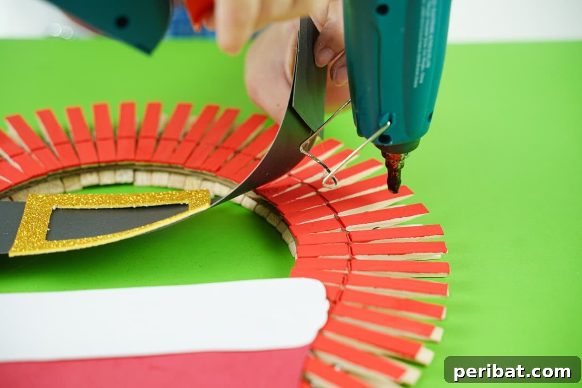Craft a Delightful Santa Hat Wreath for Christmas 16 Gluing the crafted Santa belt onto the wreath.