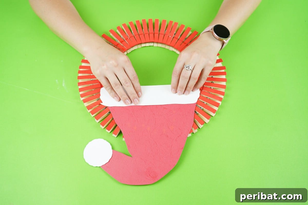 Craft a Delightful Santa Hat Wreath for Christmas 17 Gluing the red Santa hat onto the top of the craft wreath.