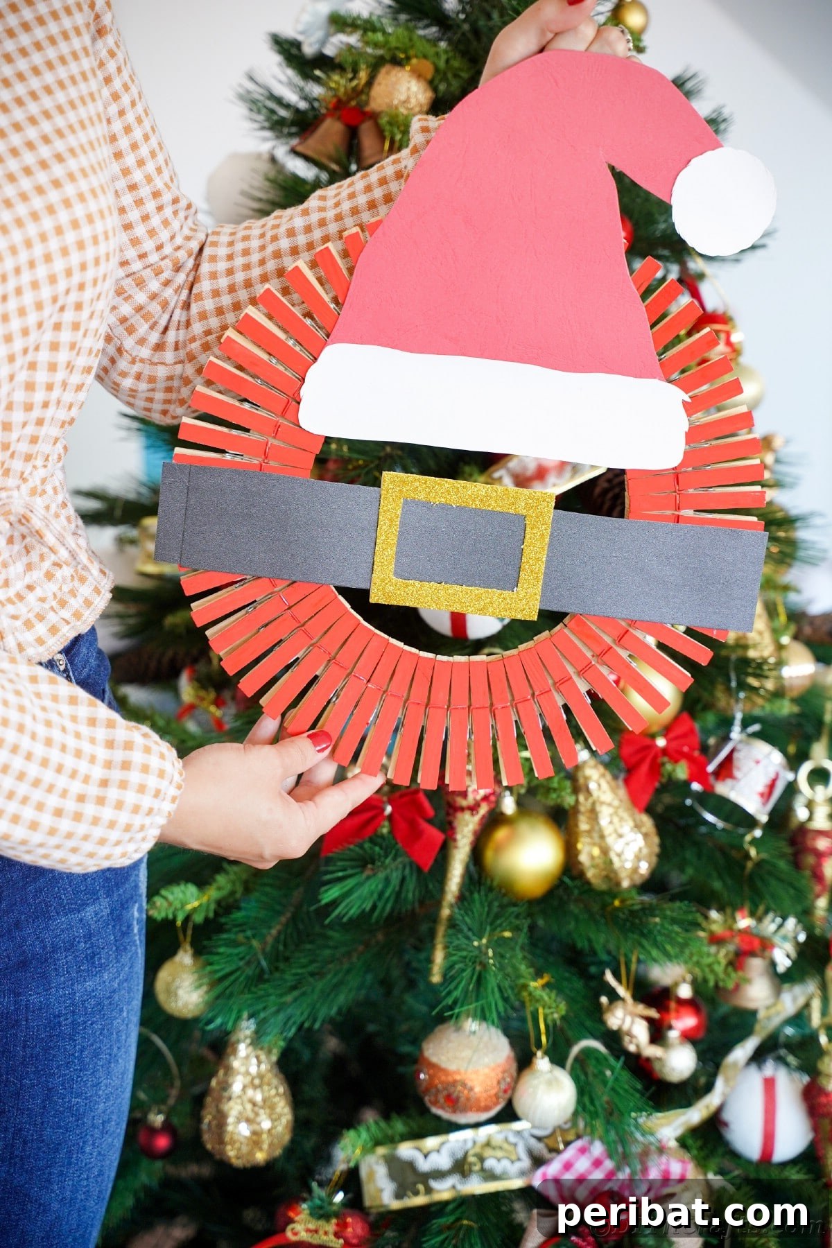 Craft a Delightful Santa Hat Wreath for Christmas 18 Woman proudly holding a finished DIY Santa hat wreath.